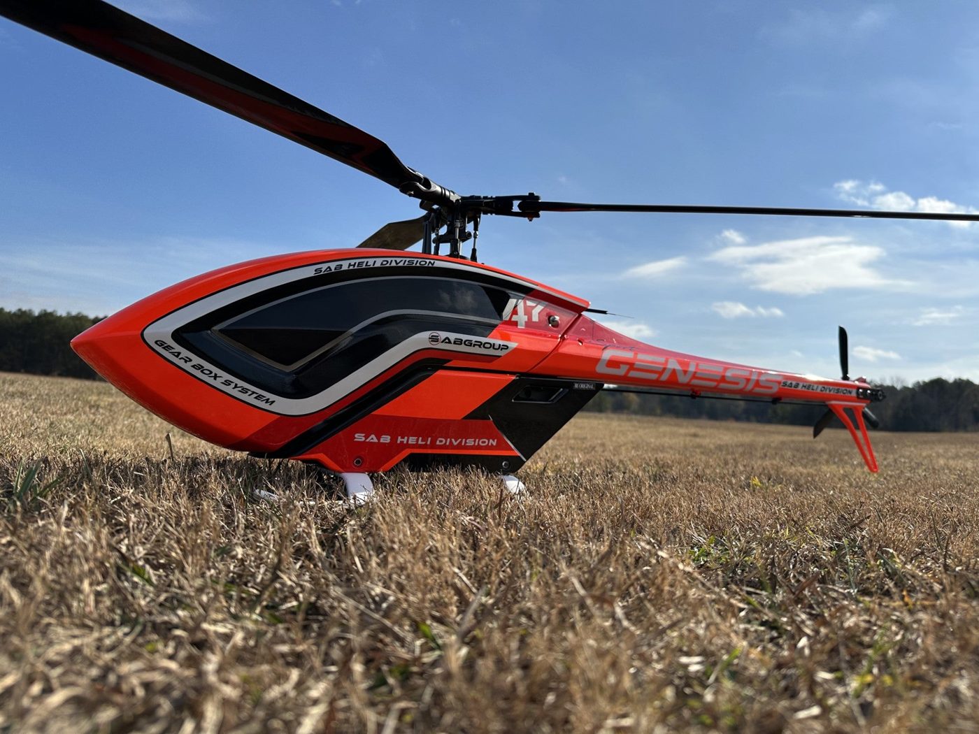 Red helicopter with a custom canopy sitting in a field