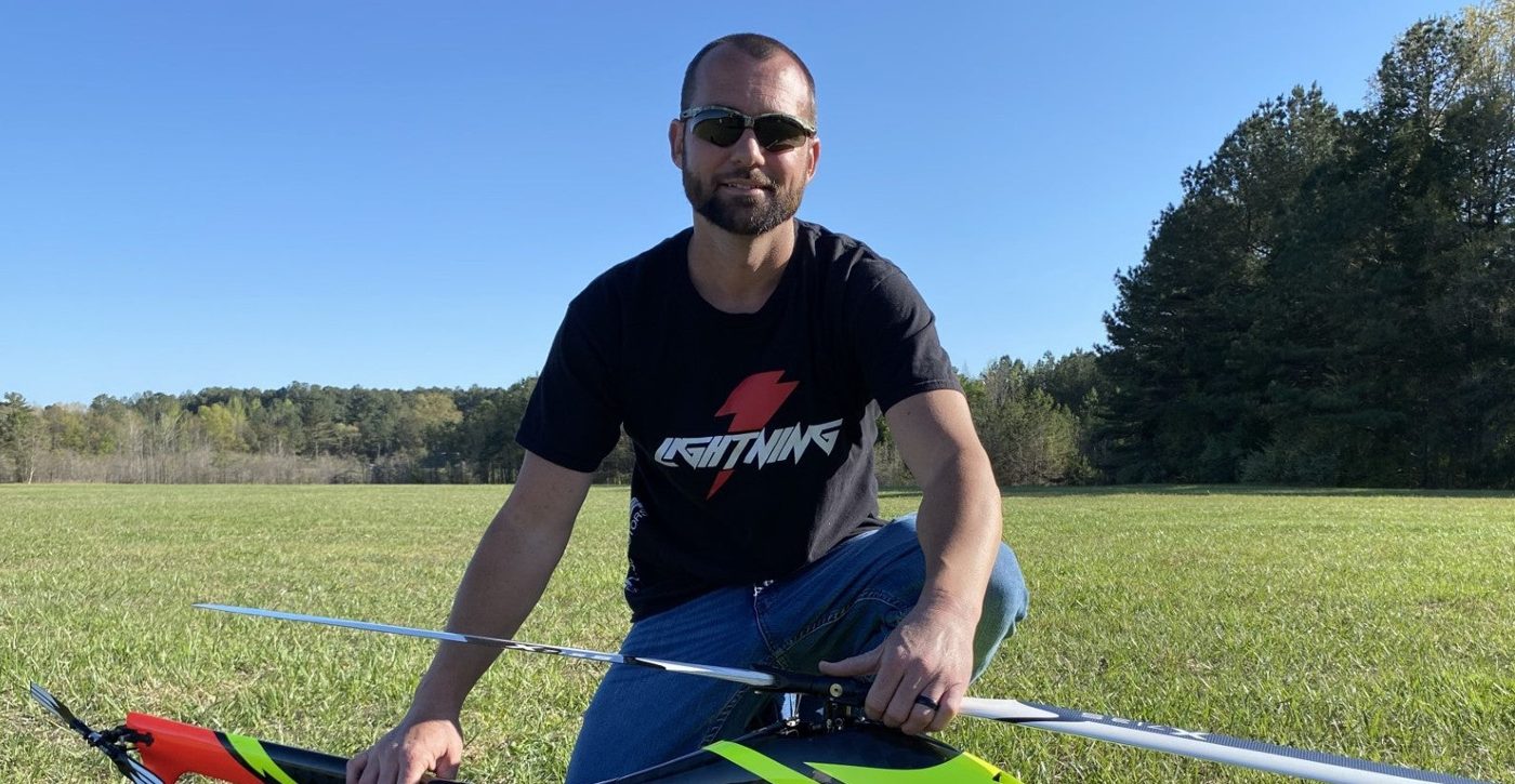 Jeff West kneeling in a field with an RC helicopter
